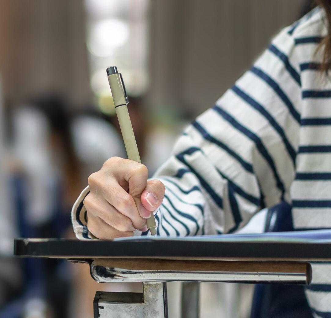 Exam at school with student's taking educational admission test in class, thinking hard, writing answer in university classroom, education and world literacy day concept